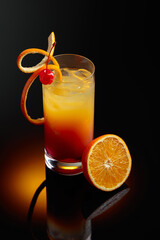 Cocktail tequila sunrise on a black reflective background.