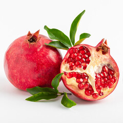 Healthy ripe pomegranate fruit and half of a juicy pomegranate with leaves on a white background.