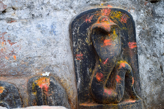 Stock photo of old snake temple in Mailar Karnataka India. Stone idol carved in blacks tone, turmeric powder and vermillion and flower offering on snake idol for worshiping . blur background.