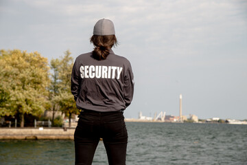 Female security guard in uniform and mask watching over harbor area