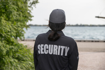 Female security guard in uniform and mask watching over harbor area