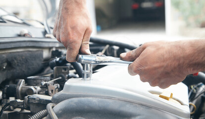 Mechanic repairing car with ratchet wrench.