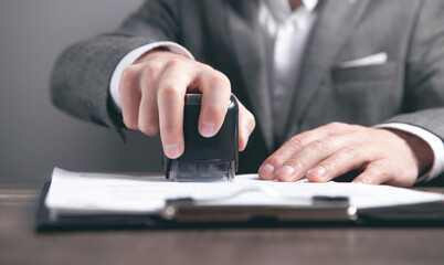 Businessman puts a stamp on the documents in the office.