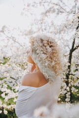 Blonde woman with cherry tree flowers in her hair, outdoors in a garden on spring day.