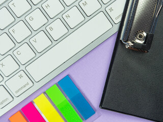 Top view above of purple desk table with keyboard, and paper. Workplace, Flat lay. Office work conception.