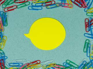 School conception, colorful school paper clips and yellow sticker for your copy space on a blue background. Back to school. Flatlay, top view.