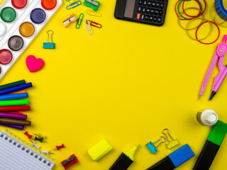 School conception, multicolored paints, pencils, markers and paper clips. School calculator and other items for the student and school on a yellow background. Flatlay, top view, copy space.