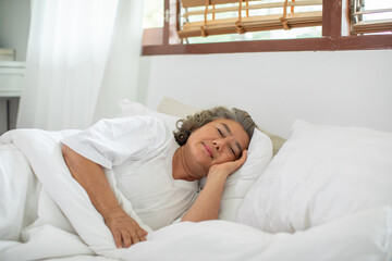 Asian Elderly woman with white hairs close eyes smile sleep and sweet dream on bed in cozy bedroom...