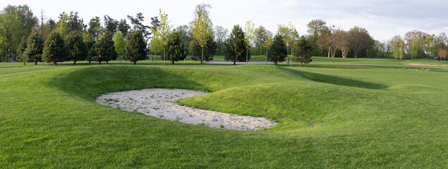 Golf course, abandoned sand trap. Panorama of golf course, lawn grass and trees growing on the territory. Golf course.