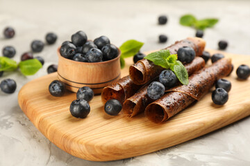 Delicious fruit leather rolls and blueberries on grey table, closeup