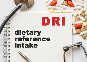 Page in notebook with DRI on white background with stethoscope and group of pill. Medical concept. Term and abbreviation. dietary reference intake