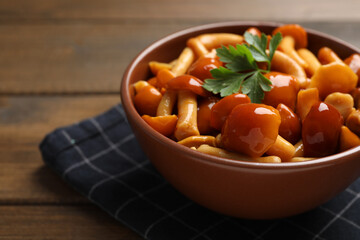 Tasty marinated mushrooms in bowl on wooden table, closeup. Space for text