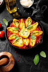 Stuffed pasta shells with spinach and ricotta served with parmesan cheese and fresh basil leaves.Healthy vegetarian food recipe. Black background.
