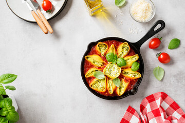 Stuffed pasta shells with spinach and ricotta served with parmesan cheese and fresh basil leaves.Healthy vegetarian food recipe. Light gray background. Top view