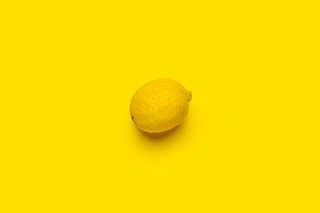 whole ripe lemon on a bright yellow background. Top view, flat lay