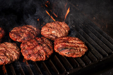 High angel view homemade meat BBQ burgers patties for hamburger cooking on flaming grill barbecue...