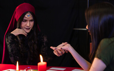 Asian witch examining hand of client