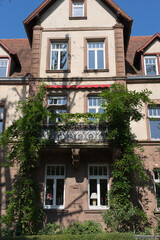 Fototapeta na wymiar Karlsruhe, Germany - Sept. 11, 2020: closeup of an old historic building with a scenic balcony and a leafy facade