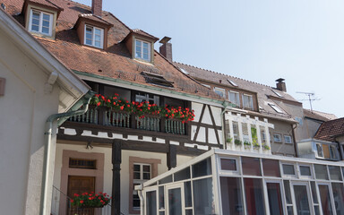 Holiday at home: balcony with red flowers on  an old half-timbered house, in the fore a modern winter garden