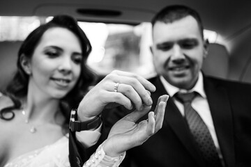 focus on hands. bride and groom in back seat of car. Renting a car for wedding.