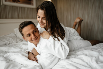 Fototapeta premium A couple in love lying on a bed in bathrobes