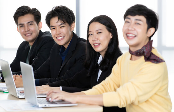 A group of multi-sex colleagues businesspeople, tomboy and transgender gay, working together with happy and intimate manner with laptop notebook computer in office