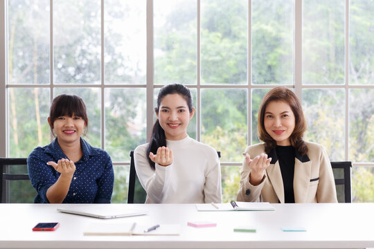 Three Beautiful And Self-confident Businesswomen Sitting In Office And Showing Hand Sign Language Skill In The Same Action