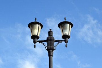 Fototapeta na wymiar Close Up View of Black Iron Traditional Street Lamp against Blue Sky 