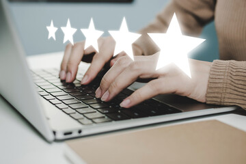 5 star rating. business woman hand working on laptop with five star button on visual screen to...