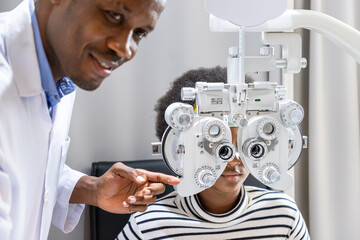 African young woman girl doing eye test checking examination using phoropter in clinic or optical shop. Eyecare concept.