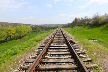 Railway on the green meadow. Rails and sleepers. Railway tracks in rural areas. Green meadows and young trees