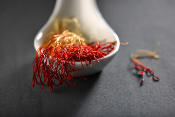 Exotic saffron strings in a white spoon. Aromatic and expensive cooking ingredient.