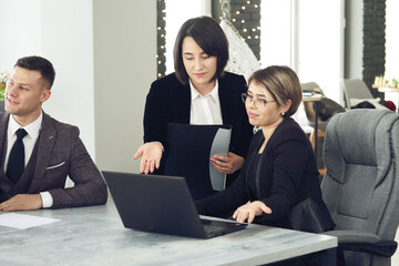 Two young business women in the office, analyzing information looking into a laptop
