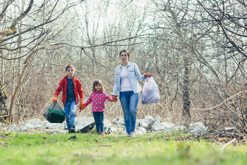 Naklejka na ściany i meble Young family mother with two children volunteers clean the spring park, collect garbage and plastic bottles, spend time together, learn to take care of the environment and take care of it