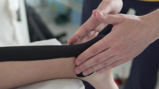Dr. Traumatologist glues the tape on the athlete's ankle, close-up of the leg. kinesiology therapeutic tape, Kinesio tape, k-tape