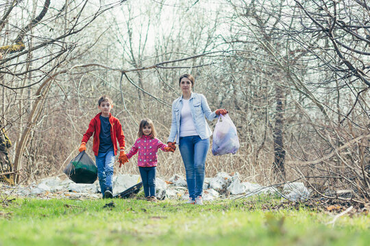 Young Family Mother With Two Children Volunteers Clean The Spring Park, Collect Garbage And Plastic Bottles, Spend Time Together, Learn To Take Care Of The Environment And Take Care Of It