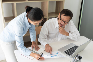 Obraz premium Senior and young businessman colleagues discuss online project to learning new skills or Coaching Business Team with young intern looking at pc screen in the office.