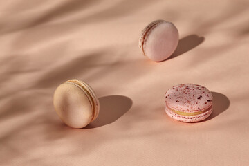 Three macarons on pastel beige background with shadow