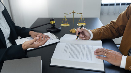 law,libra scale and hammer on the table, 2 lawyers are discussing about contract paper, law matters...