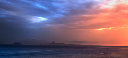 Obraz premium mountains on the horizon with foreground sea and cloudy sky