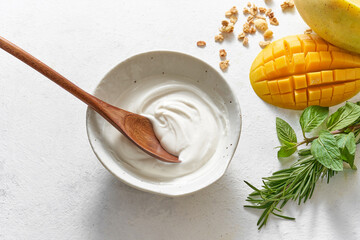 Homemade breakfast fresh colorful decoration mixed yogurt granola with mango, fig, cereal, rosemary, mint on white background