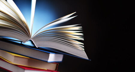 A composition with an open book lying on a stack of other books