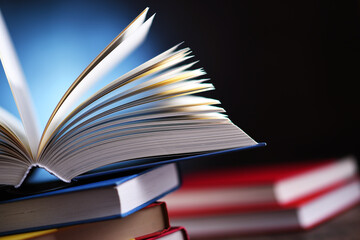 A composition with an open book lying on a stack of other books