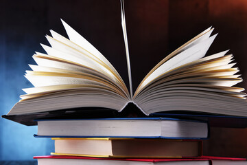 A composition with an open book lying on a stack of other books