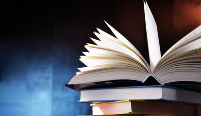 A composition with an open book lying on a stack of other books