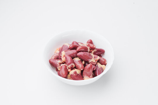 raw chicken hearts in a white plate on a white background. Close-up. 