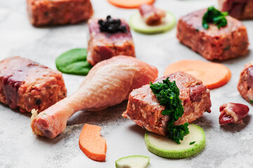 Composition with raw square cutlets and raw chicken legs on a light background. Natural dog food. 