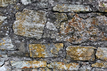 Part of the old, weathered wall, made of natural stones and bricks, is dominated by gray.