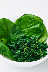 spinach (fresh and freeze spinach) blanch. on a white plate on a light background. Top view. Mockup