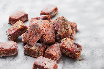 Composition with raw square cutlets on a light background. Natural dog food. Diet for dogs BARF. Close up